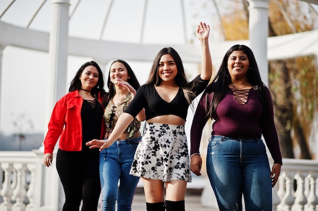 Grupo de cuatro muchachas latinas felices y bonitas de Ecuador posó en la calle contra el arco antiguo.