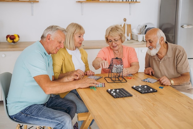 Grupo de cuatro personas mayores alegres jugando al bingo en un hogar de ancianos