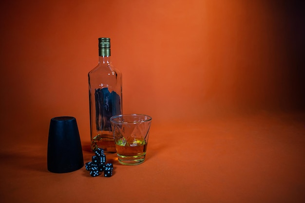 Grupo de dados negros junto a un vaso, sobre la mesa una botella y un vaso lleno de whisky