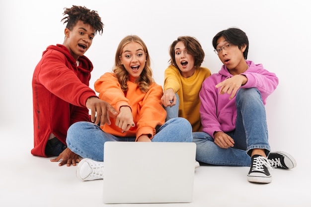 Grupo de adolescentes alegres isolado, olhando para o laptop, acenando