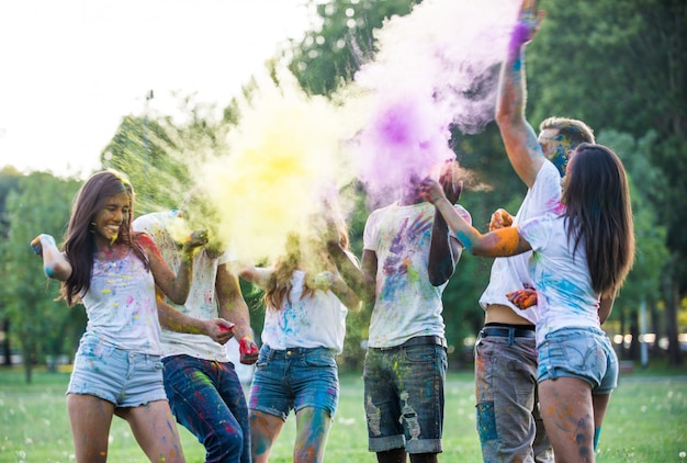 Grupo de adolescentes brincando com cores no festival de holi, em um parque