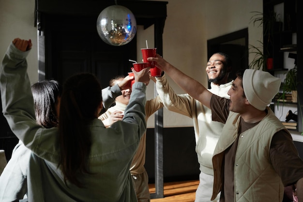 Grupo de adolescentes brindando com copos plásticos enquanto se divertem em uma festa