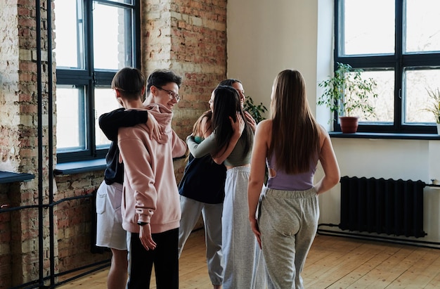 Grupo de adolescentes felizes dando abraços uns aos outros antes da repetição no estúdio