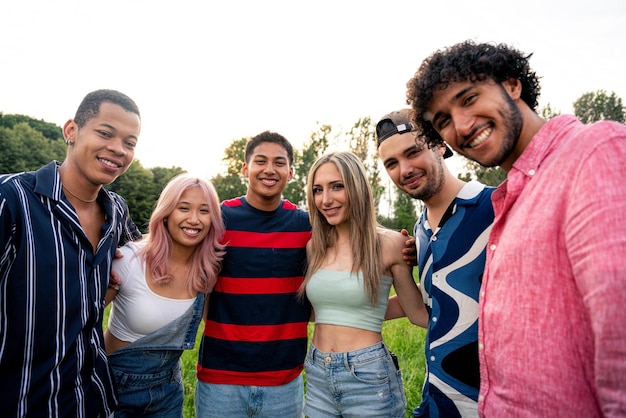 Grupo de adolescentes multiétnicos passando tempo ao ar livre em um piquenique no parque