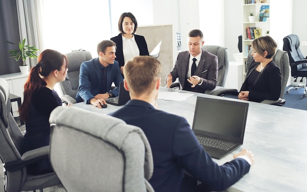 Grupo de advogados de jovens empresários de sucesso se comunicando em uma sala de conferências enquanto trabalham em um projeto