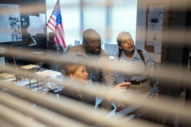 Foto grupo de agentes do fbi assistindo registro da câmera de segurança dentro do escritório