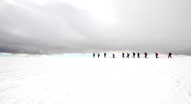 Foto grupo de alpinistas caminhando pelas montanhas cobertas de nevexaxa