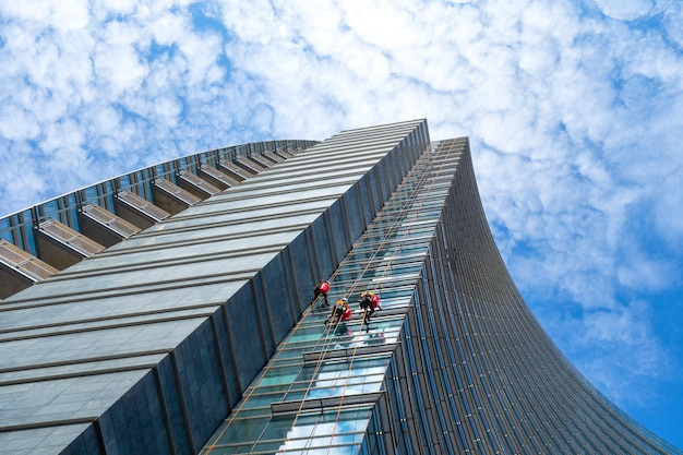 Foto grupo de alpinistas em serviço de limpeza de janelas de edifícios arranha-céus