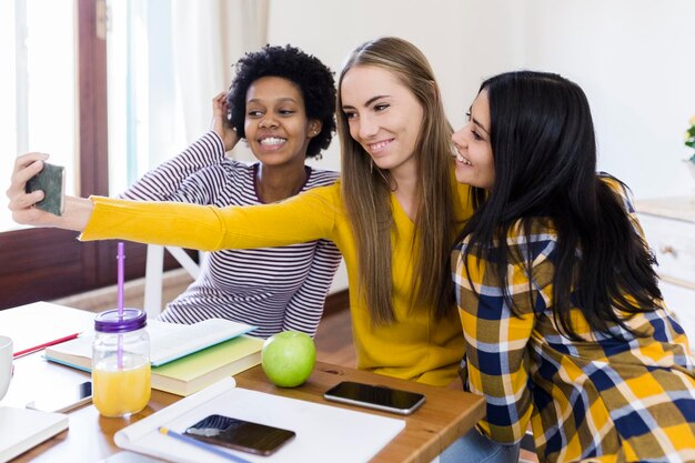 Foto grupo de alunas tirando selfie à mesa em casa