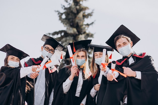 Grupo de alunos comemorando a formatura juntos e usando máscaras