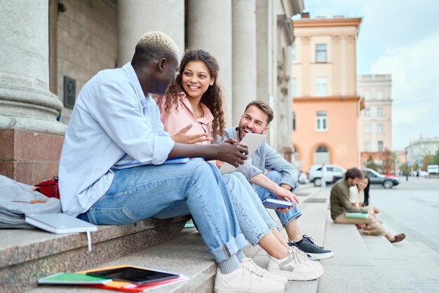 Grupo de alunos estão conversando sentados nos degraus