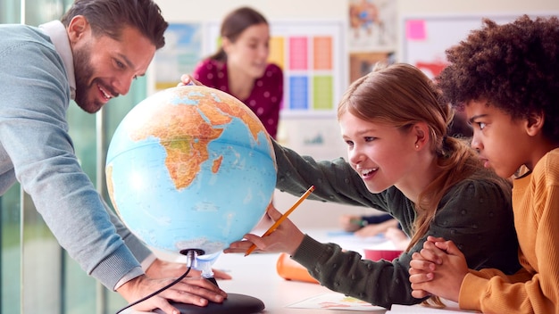 Foto grupo de alunos multiculturais com professores em sala de aula olhando para o globo na aula de geografia