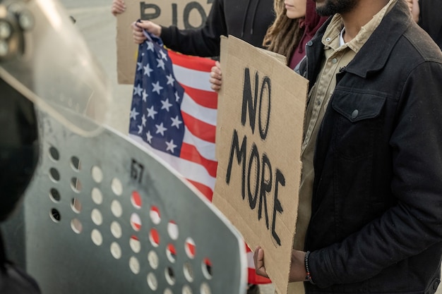 Foto grupo de americanos segurando faixas de papelão enquanto instava o governo em manifestação, as forças policiais com escudos contra a multidão