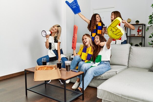 Foto grupo de amigas jovens assistindo e apoiando uma partida de futebol em casa