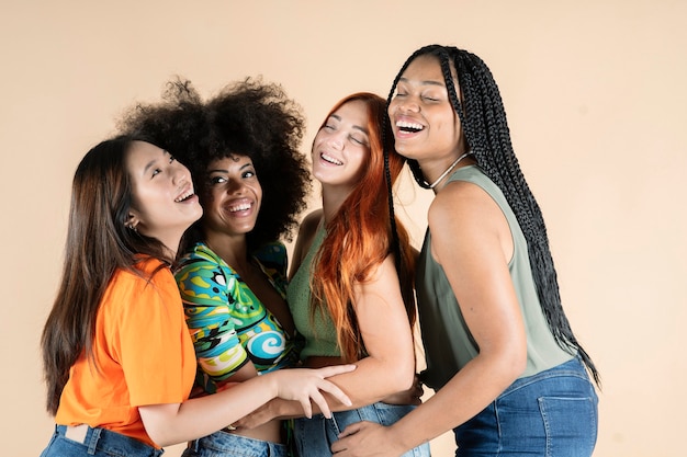 Grupo de amigas multiétnicas, abraçando-se, posando no estúdio, sorrindo felizes