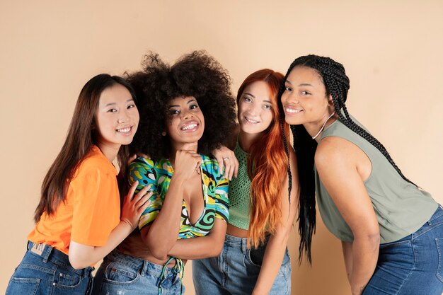 Foto grupo de amigas multiétnicas, abraçando-se, posando no estúdio, sorrindo felizes