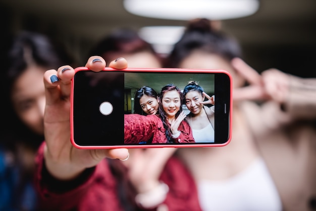 Grupo de amigas tirando uma selfie junto com um conceito de amizade no celular