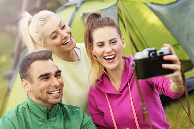 grupo de amigos acampando na floresta e tirando selfie