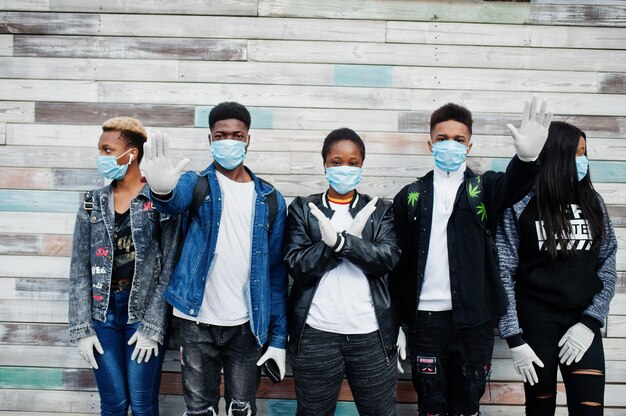 Grupo de amigos adolescentes africanos usando máscaras médicas protegem contra infecções e doenças quarentena do vírus coronavírus.