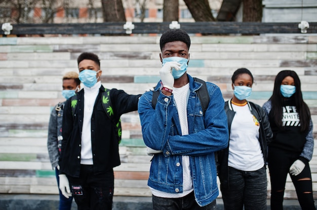 Grupo de amigos adolescentes africanos usando máscaras médicas protegem contra infecções e doenças quarentena do vírus coronavírus.