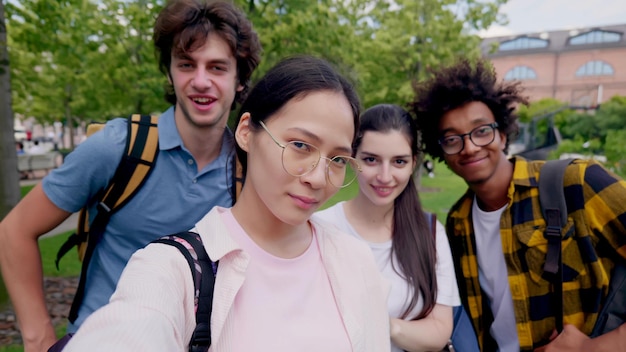 Foto grupo de amigos adolescentes multiétnicos tirando selfie ao ar livre e sorrindo para a câmera