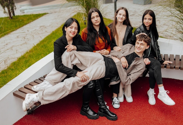 Grupo de amigos adolescentes sorridente e feliz vestindo roupas casuais passando tempo juntos posando e conversando uns com os outros perto do prédio da faculdade em um dia de outono