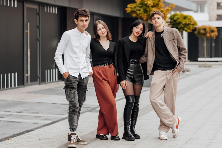 Foto grupo de amigos adolescentes sorridente e feliz vestindo roupas casuais passando tempo juntos posando e conversando uns com os outros perto do prédio da faculdade em um dia de outono