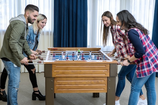 Grupo de amigos alegres jogando futebol de mesa