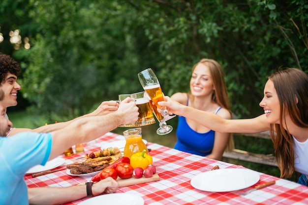 Grupo de amigos almoçando e brindando com cerveja