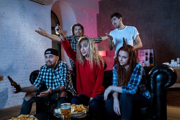 Grupo de amigos assistindo a um jogo de TV em casa