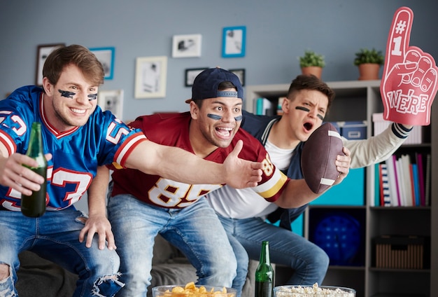 Grupo de amigos assistindo futebol em casa