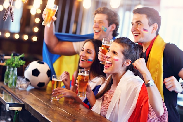 Grupo de amigos assistindo jogo de futebol no bar