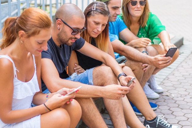 Grupo de amigos assistindo telefones inteligentes - geração Millennials