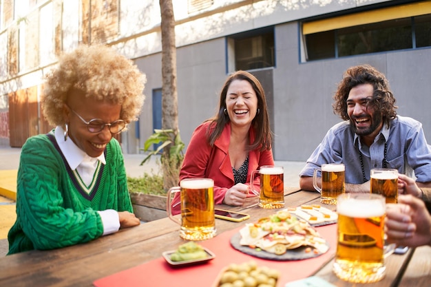 Grupo de amigos bebendo cerveja e rindo no terraço ao ar livre