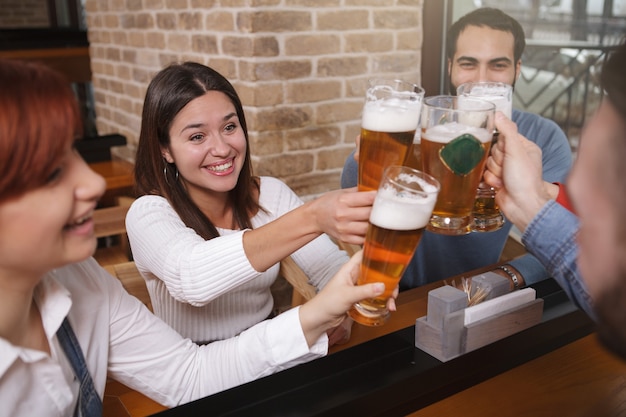 Grupo de amigos bebendo cerveja no bar juntos