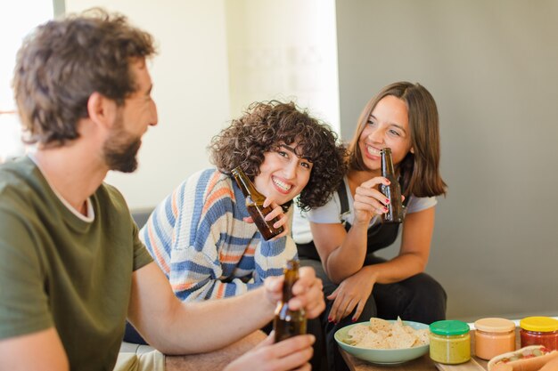 Foto grupo de amigos bebendo cerveja, relaxados e felizes na nova casa