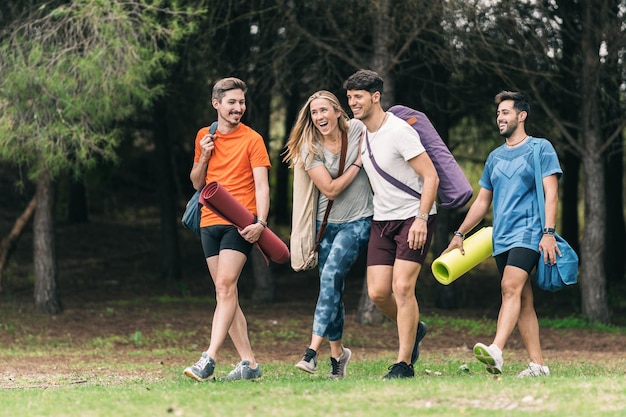 Grupo de amigos brincando e rindo a caminho de fazer ioga no meio da floresta