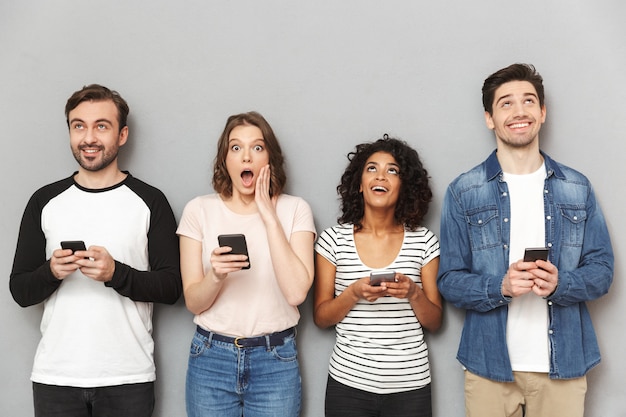 Grupo de amigos chocados emocionais usando telefones celulares.