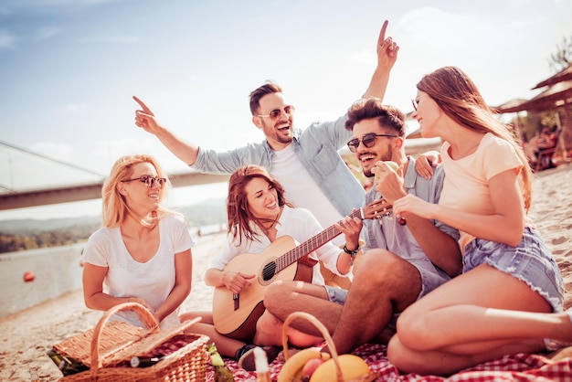 Grupo de amigos com guitarra se divertindo na praia