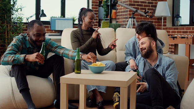 Grupo de amigos conversando sobre positividade e bebendo cerveja, conversando sobre memórias e amizade. Pessoas se divertindo e se relacionando com atividades relaxantes de passatempo em casa.