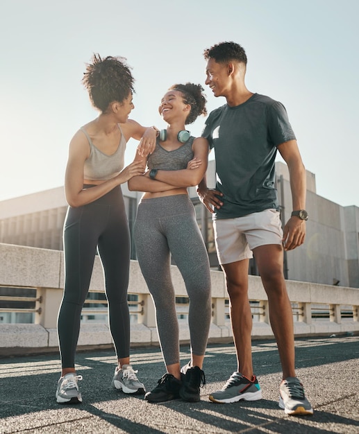 Foto grupo de amigos correndo na cidade sorri e ri juntos na estrada depois de correr na cidade para treino de verão ao ar livre, exercício físico e treinamento para maratona atletas negros felizes, homens e mulheres, após cardio