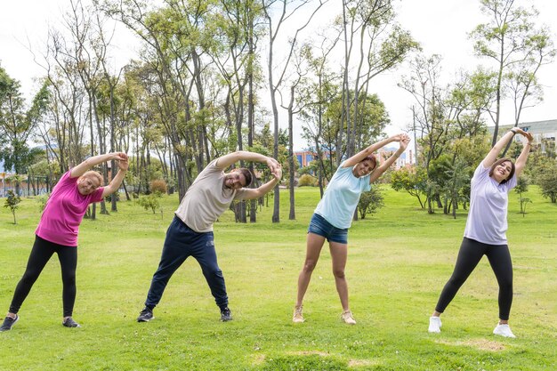 Grupo de amigos de diferentes idades, estendendo-se no parque