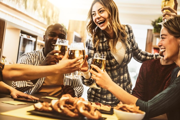Grupo de amigos de raça mista brindando com copos de cerveja no pub da cervejaria