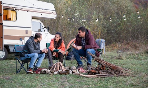 Grupo de amigos desfrutando de seu tempo juntos nas montanhas, acampando com van de campista retrô.