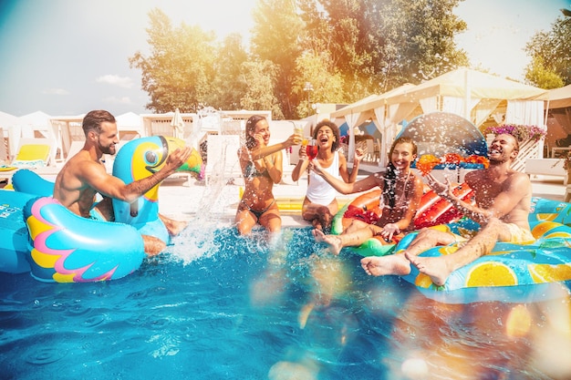 Grupo de amigos em traje de banho desfruta em uma piscina