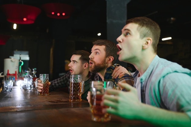 Grupo de amigos entusiasmados no bar de cerveja assistindo jogo de esportes