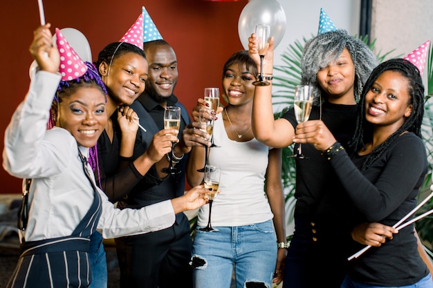 Grupo de amigos felizes africanos bebendo champanhe e comemorando o ano novo. Festa de Ano Novo. Festa de aniversário