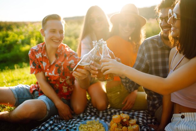 Grupo de amigos felizes aplaude bebendo cervejas no parque de verão conceito de amizade ou feriado