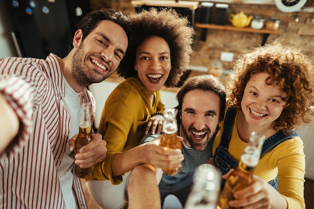 Foto grupo de amigos felizes bebendo cerveja e se divertindo enquanto tira selfie na festa em casa,