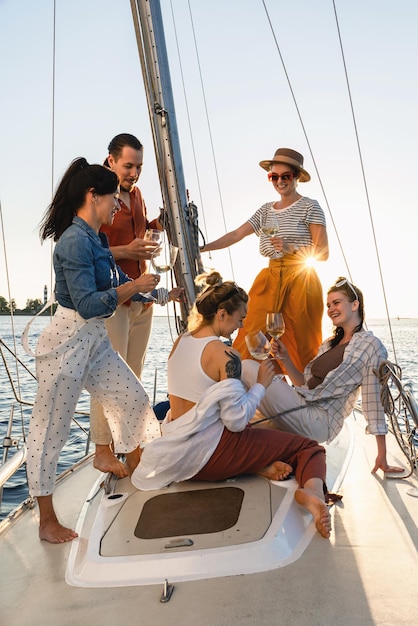 Grupo de amigos felizes bebendo vinho e relaxando no veleiro durante a navegação no mar